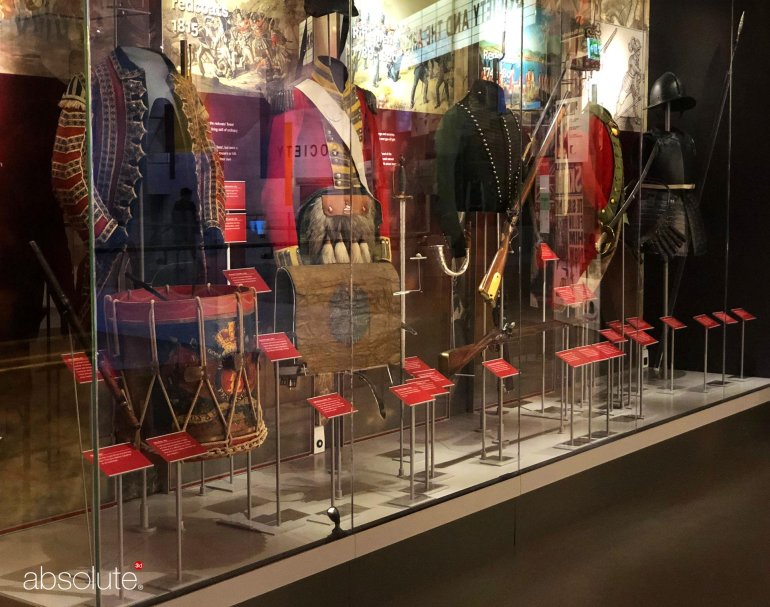 Uniforms showcased in a National Army Museum exhibition, with descriptive information displayed in pinnacle label holders.